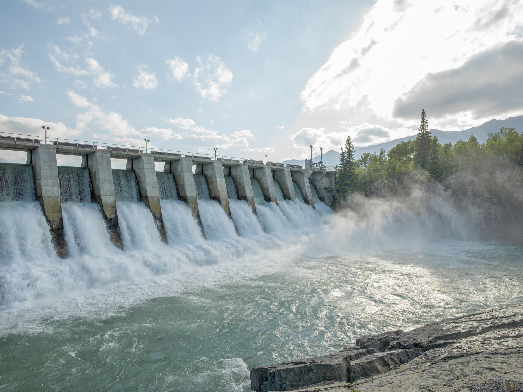  Erzeugung nachhaltiger Energie durch eine Wasserwerk vor einem blauen Himmel und Wald